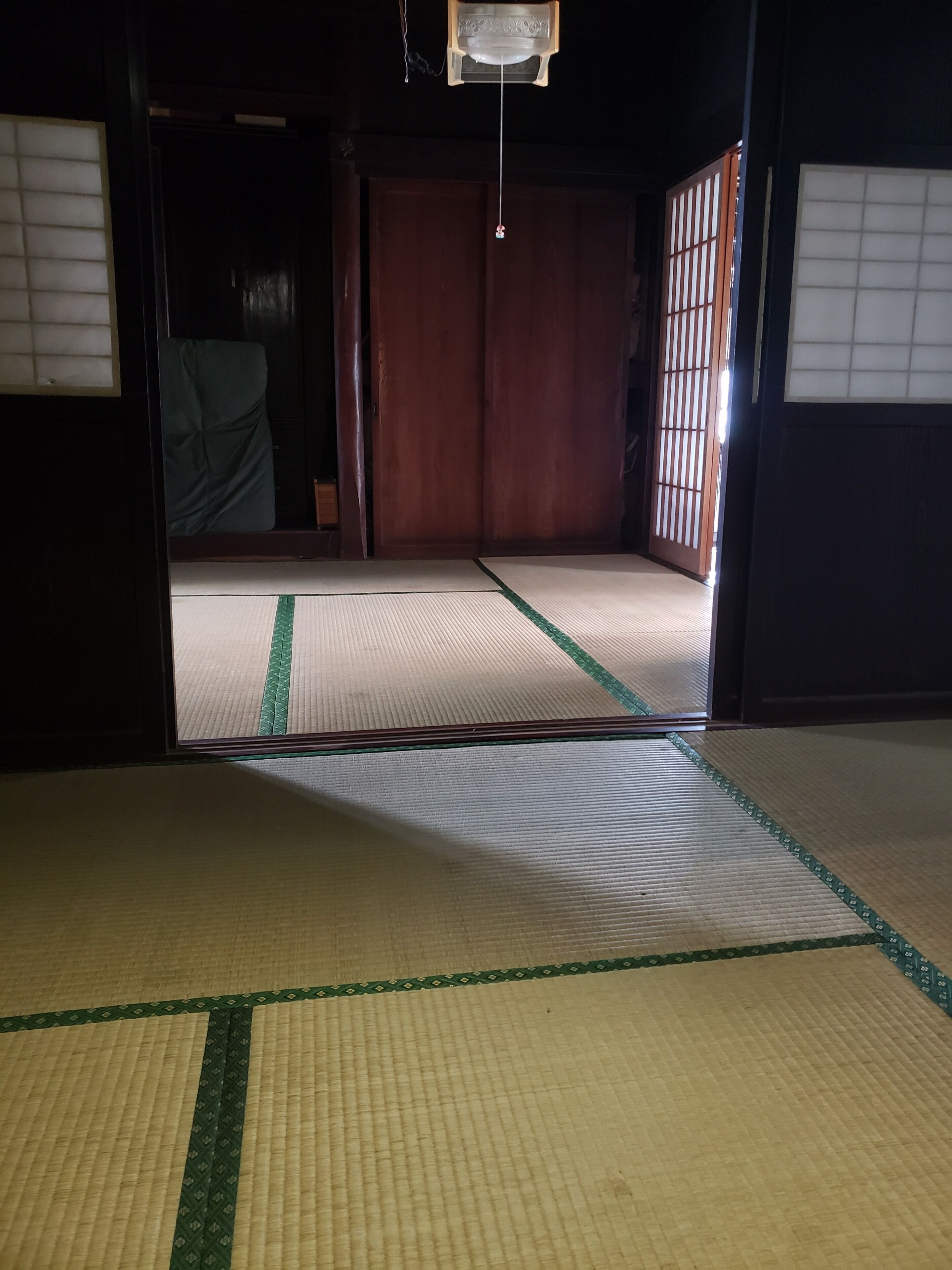 Ett traditionellt japanskt rum med tatamimattor på golvet, skjutdörrar och en hängande lampa.