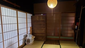 Une pièce de style japonais traditionnel, avec un sol recouvert de tatamis, des portes coulissantes et un luminaire suspendu.