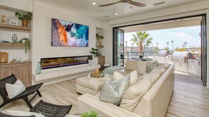 Una sala de estar moderna con un televisor grande, asientos cómodos, una chimenea y vistas al exterior.