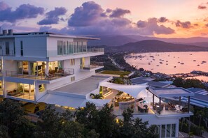 A modern multi-story hotel with a rooftop terrace, offering views of a coastal bay with boats. - Unique Boutique Resort (Koh Samui)