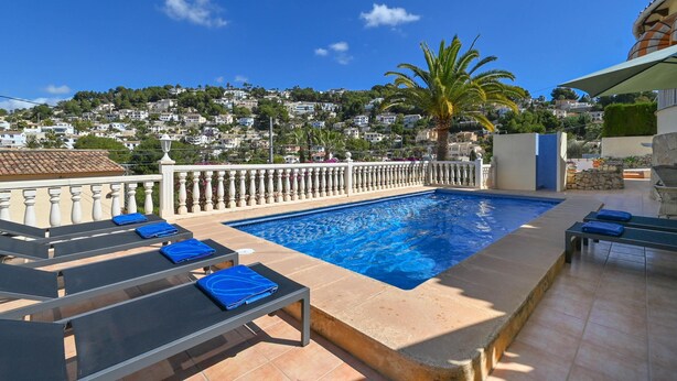 Ein Swimmingpool mit Liegestühlen und Blick auf eine Stadt am Hang.