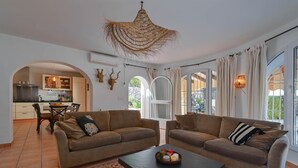 Ein Wohnzimmer mit zwei Sofas, einem Couchtisch und einem Essbereich, der durch einen Bogen sichtbar ist.