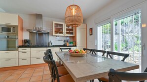 Eine moderne Küche mit weißen Schränken, einem Edelstahlherd und einem Essbereich mit einem Holztisch und Stühlen.