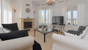 A living room with a fireplace, a television, and a chandelier. - Large and nice villa  with private pool in Benitachell, on the Costa Blanca, Spain for 8 persons (Benitachell)