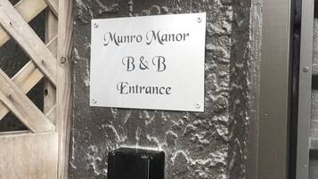 A sign for Munro Manor B&B Entrance, a keypad door lock, and a wall-mounted intercom.