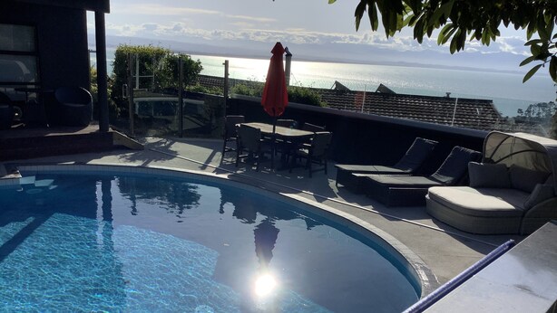 A swimming pool with a view of the sea and mountains.