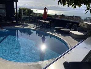 A swimming pool with a view of the sea and mountains.