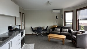A compact living space with a kitchenette, a dining area, and a seating area with a sofa and armchairs.