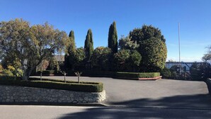A parking lot with a stone wall and neatly trimmed hedges.