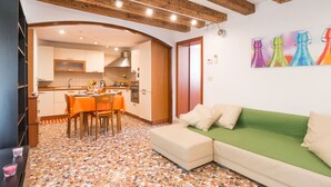 A cozy living area with a green sofa, a dining table with chairs, and a kitchen in the background. - Typische venezianische Wohnung für Familien -  Venitian apartment  for families (Venice)