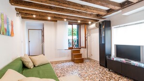 A room with a green sofa, wooden beams on the ceiling, a television, and a tiled floor. - Typische venezianische Wohnung für Familien -  Venitian apartment  for families (Venice)