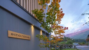 A building with a sign reading "echo rocks" and a view of a mountainous landscape in the background. - Echo Rocks (Hakuba)