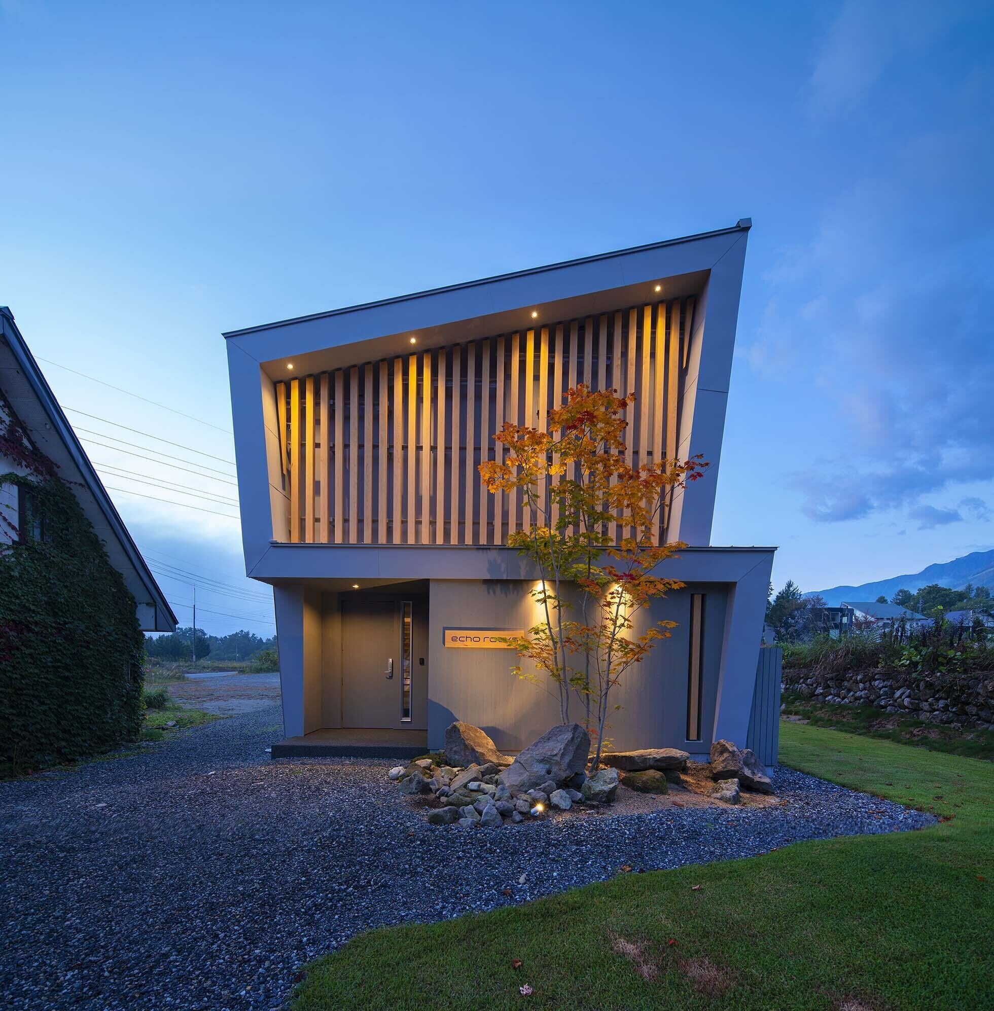 A modern two-story building with a minimalist design, featuring a flat roof and large windows.