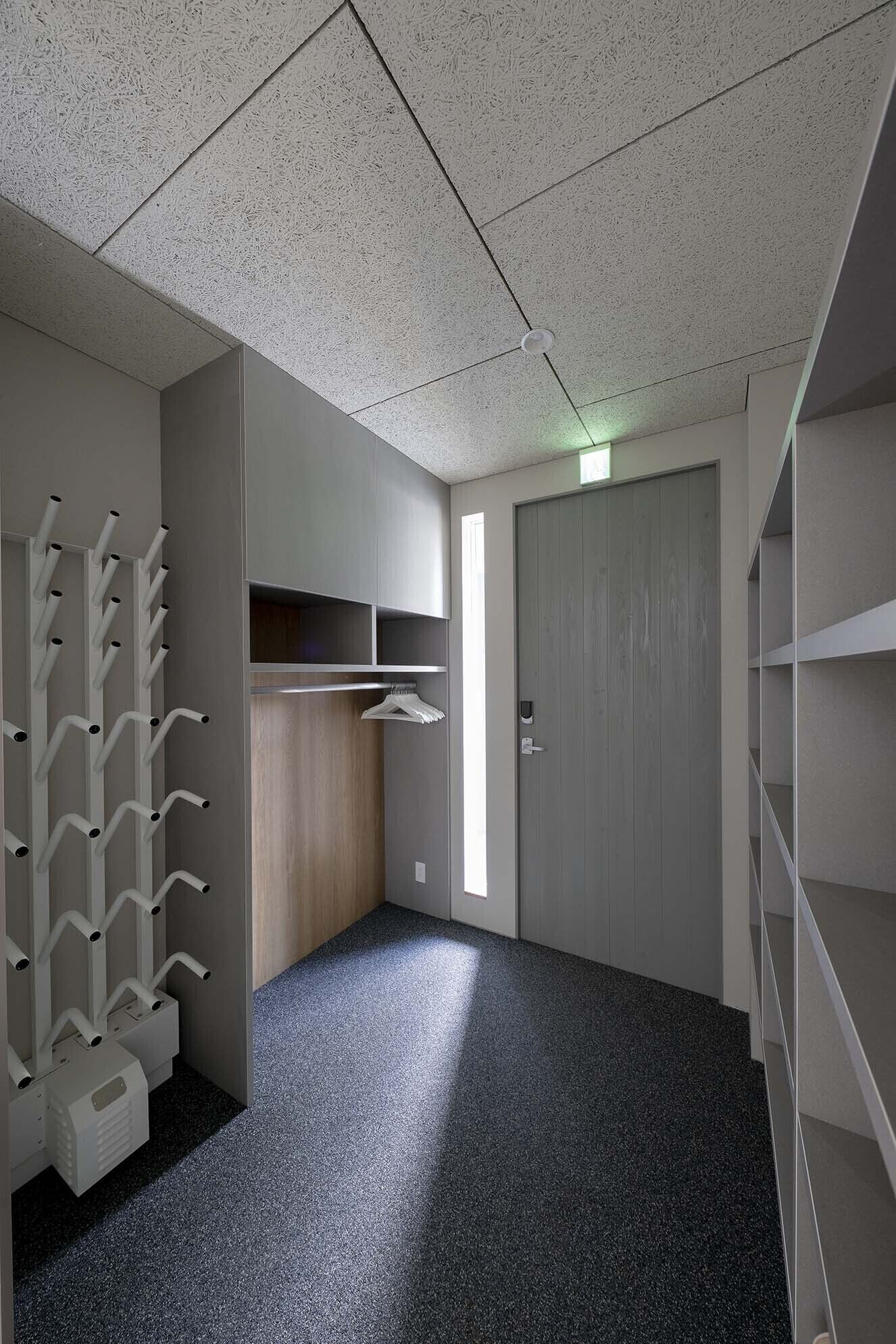 A room with a kitchenette, a wardrobe, and a coat rack.