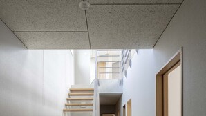 A modern interior with a staircase leading to a second floor, a hallway, and a door on the right. - Echo Rocks (Hakuba)