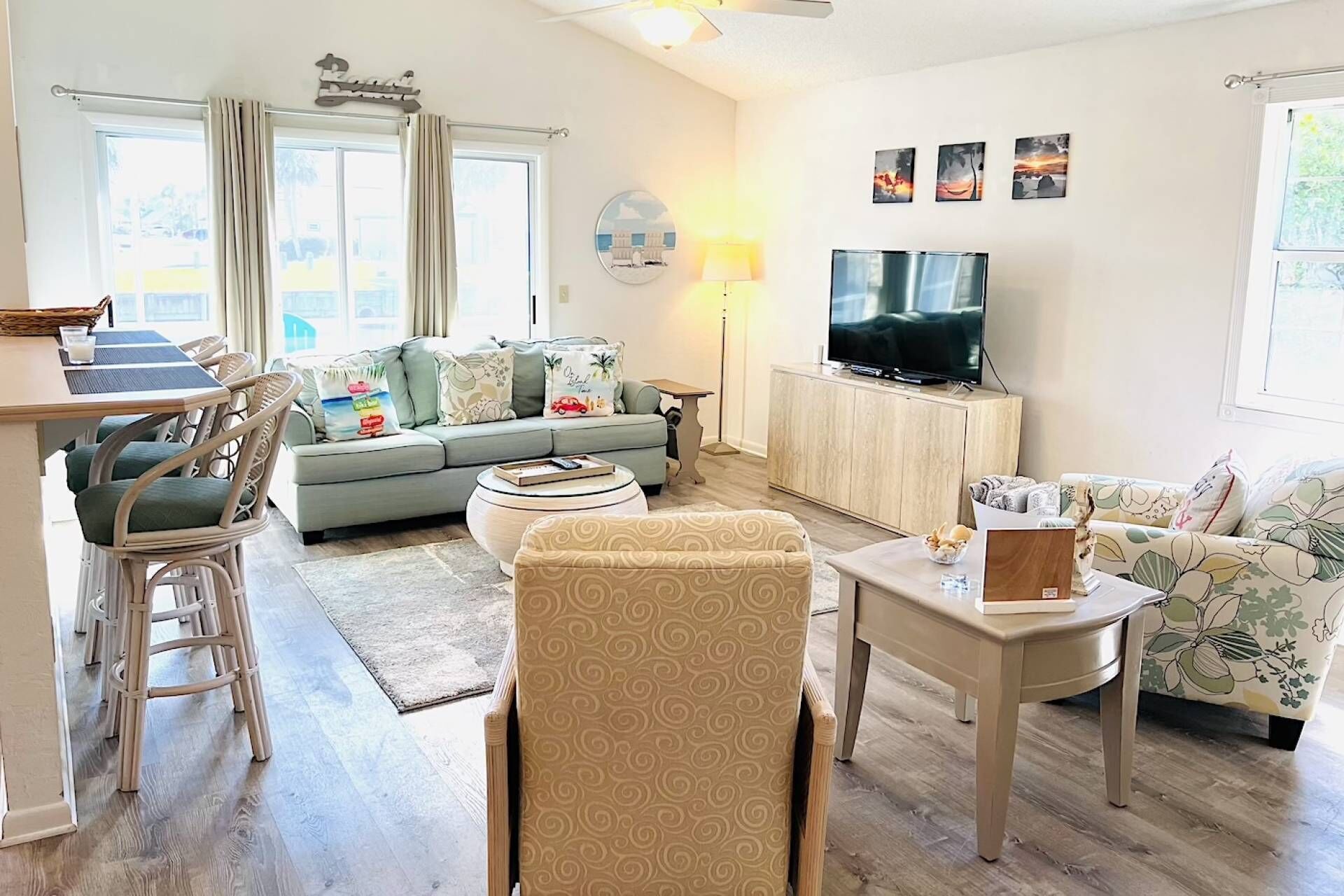 A well-lit living room with a sofa, chairs, a dining table, and a TV.