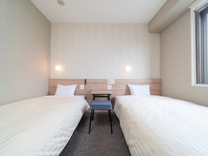 A hotel room with two beds, a small table, and two wall-mounted lights. - Super Hotel Iyosaijo (Saijo)