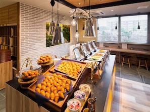 A buffet area with various food items and a seating area with a view of the outside. - Super Hotel Iyosaijo (Saijo)