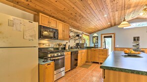 Una cocina con armarios de madera, estufa, microondas y una isla grande con frutas.
