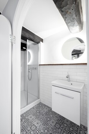 A modern bathroom with a shower, a sink, and a mirror. - Hotel zum Heidkrug (Lueneburg)