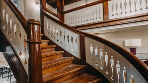 A wooden staircase with ornate balusters and a polished wood finish. - Hotel zum Heidkrug (Lueneburg)