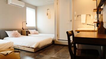 A bedroom with two beds, a wooden table, a chair, a window, and a door.