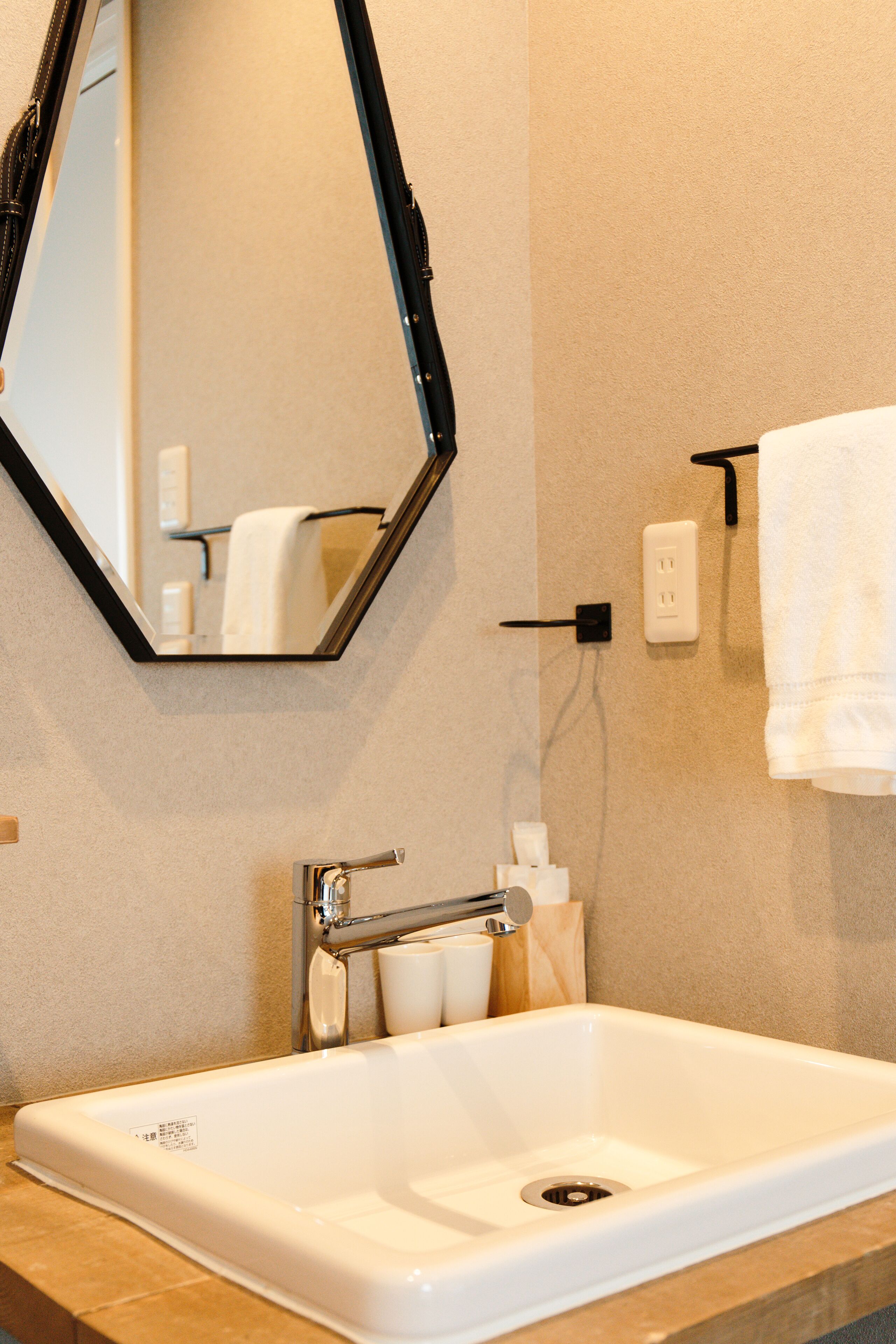 A bathroom with a white sink, a mirror, and a towel hanging on a rack.