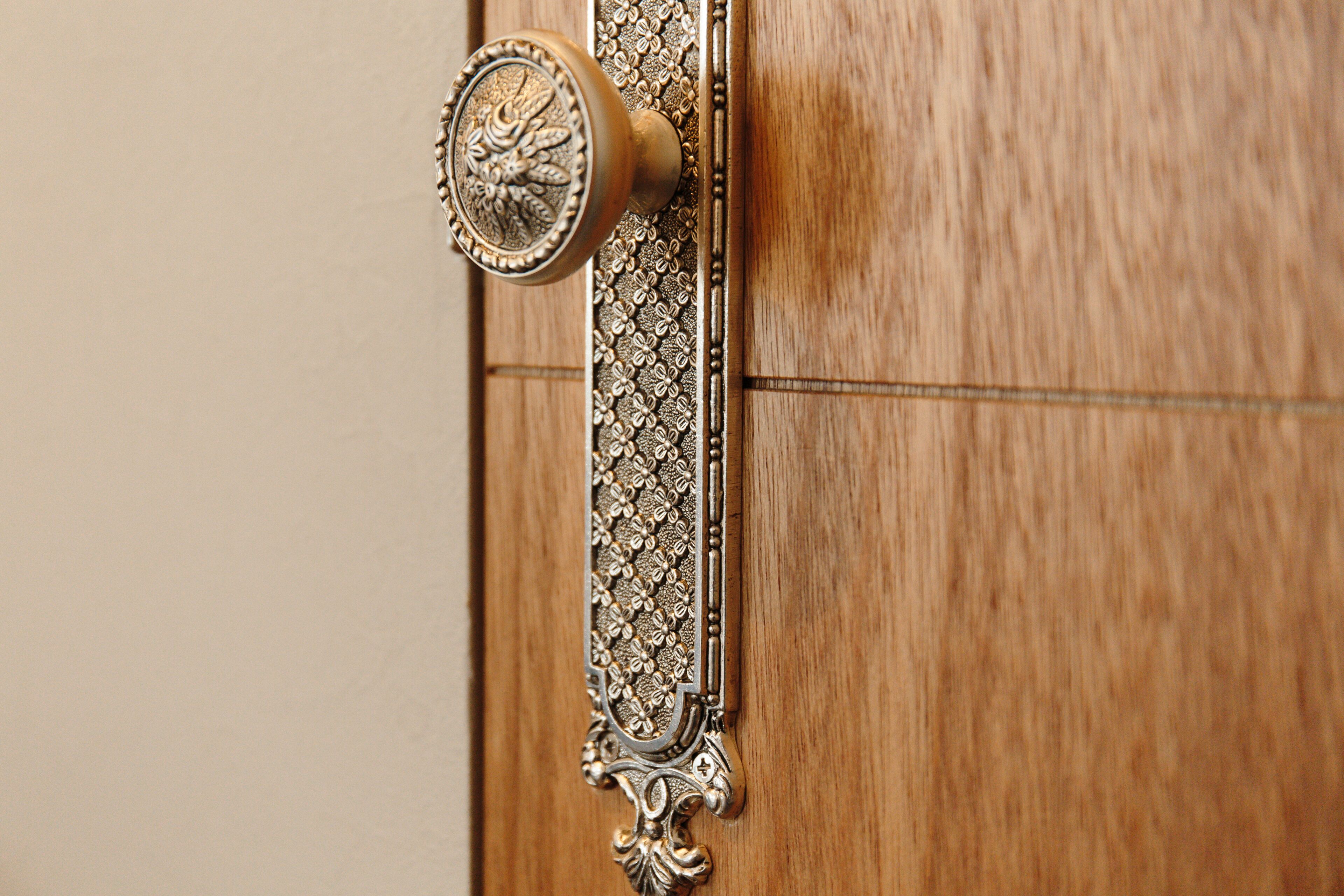 A wooden door with an ornate brass doorknob and a decorative metal strip.