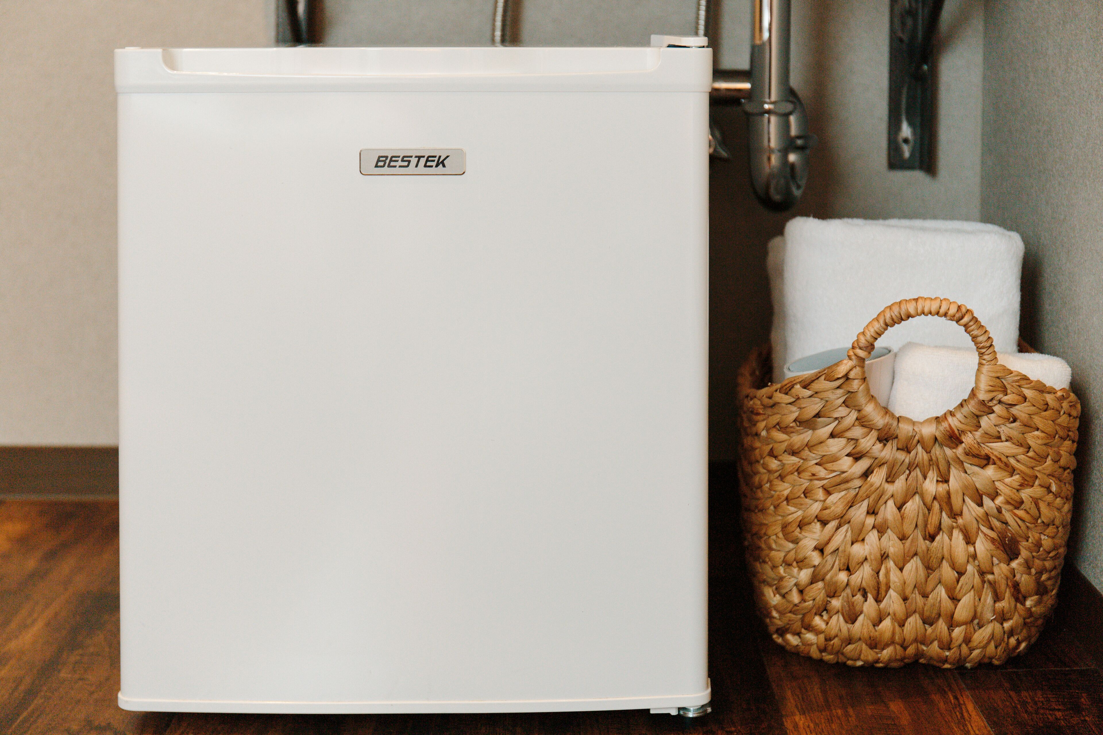 A white Bestek refrigerator next to a woven basket.
