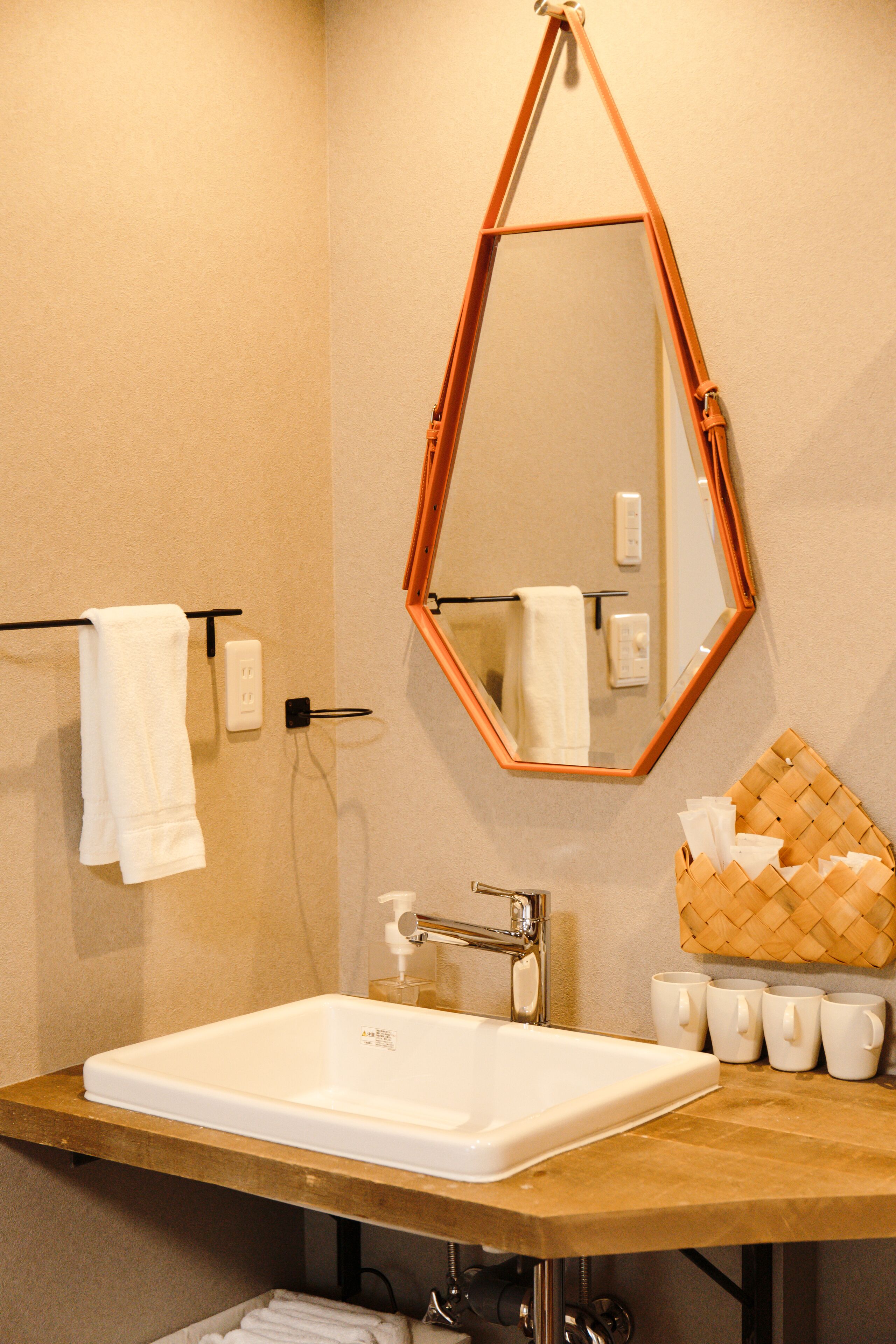 Une salle de bain avec un lavabo rectangulaire, un miroir et un porte-serviettes.