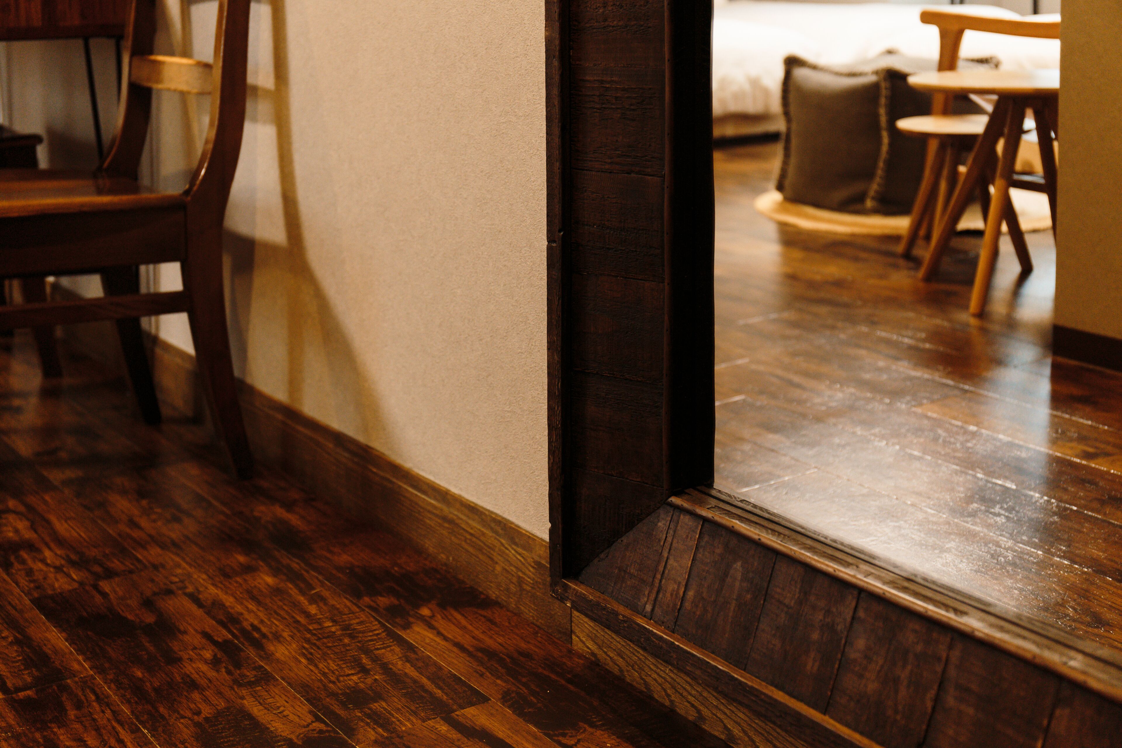 Un suelo de madera que conduce a una habitación con una cama y una silla.