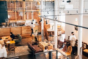 A spacious, modern interior with high ceilings, exposed beams, and a mix of seating areas including tables and chairs. - Lampstand STAY Asahikawa (Asahikawa)