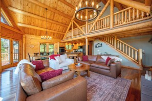 A spacious living area with leather sofas, a wooden dining table, and a kitchen in the background.