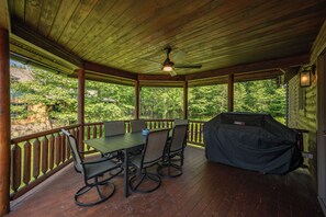 Un patio esterno coperto con tavolo e sedie, una ventola a soffitto e una griglia per barbecue.