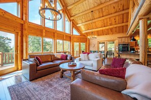 A spacious wooden cabin interior with a living area, dining space, and kitchen.