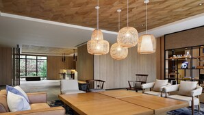 Una sala moderna con una amplia mesa de centro de madera, varios sofás e iluminación colgante de mimbre.