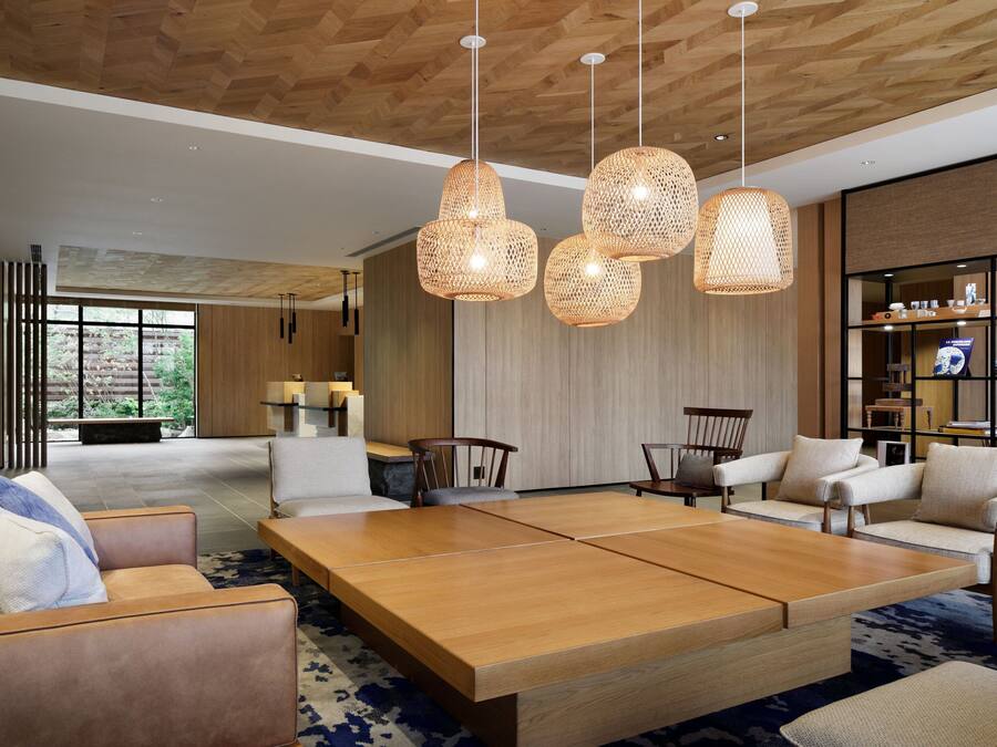 Una sala moderna con una amplia mesa de centro de madera, varios sofás e iluminación colgante de mimbre.