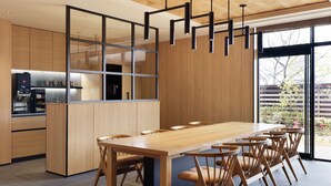 Una cocina moderna con una larga mesa de madera y sillas, horno empotrado y un amplio ventanal con vistas al exterior.