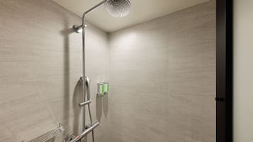 Una ducha moderna con cabezal de ducha de mano, panel de control en la pared y un perchero para toallas.