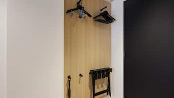 Une pièce avec une armoire en bois, une porte noire et un porte-manteau noir doté de plusieurs crochets.