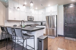 A modern kitchen with white cabinets, stainless steel appliances, and a central island with bar stools.