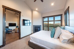 A modern bedroom with a large bed, a TV, a fireplace, and a view of the outdoors. - 2 BR on golf course, outdoor swimming pool and clubhouse, walk to hiking trails (Park City)