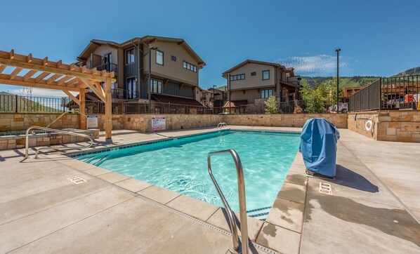 A swimming pool with a wooden pergola, a lifeguard stand, and a covered umbrella. - 2 BR on golf course, outdoor swimming pool and clubhouse, walk to hiking trails (Park City)