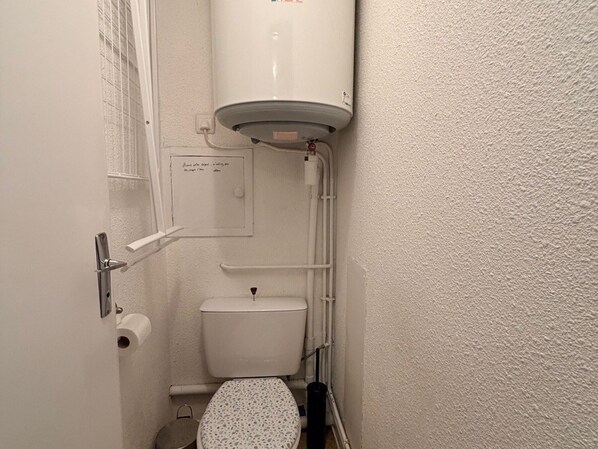 A small bathroom with a toilet, a white wall, and a white ceiling.
