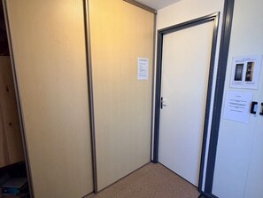 A room with a closed door, a visible closet, and a bulletin board with papers.