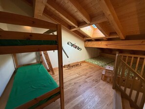 Een slaapkamer met stapelbed, dakraam, houten balken en een decoratie aan de muur.