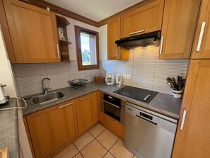 A kitchen with wooden cabinets, a stainless steel sink, a built-in oven, and a dishwasher. - High-end 4-room duplex at the foot of the slopes with parking (Les Adrets-Prapoutel)
