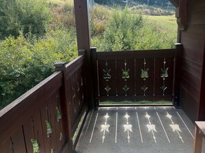 A wooden balcony with a view of a grassy field and dense shrubbery. - High-end 4-room duplex at the foot of the slopes with parking (Les Adrets-Prapoutel)