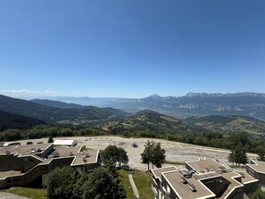 A mountainous landscape with a parking area and buildings with flat roofs.