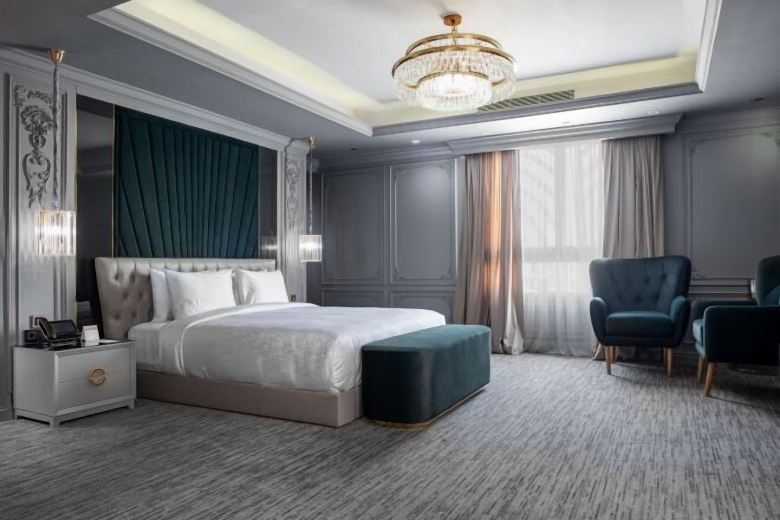 Una habitación de hotel moderna con una cama grande, una mesita de noche, una silla y una araña.